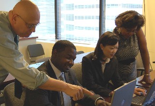 Image of group of professionals working together behind computer monitors
